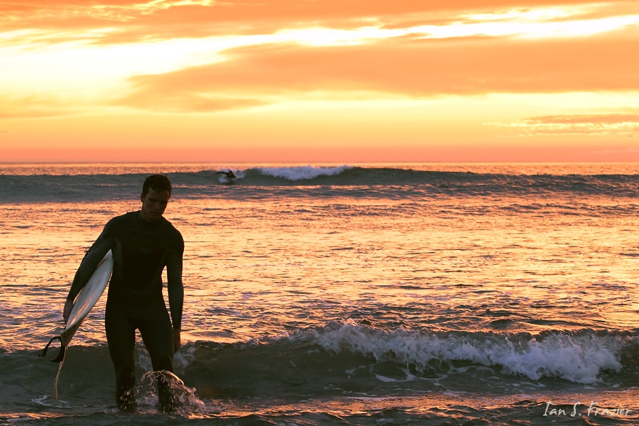 Surfer leaving ocean after sun has set